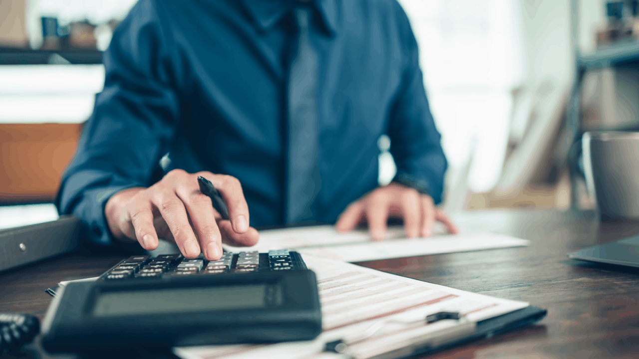 Man using calculator to review financial statements and assess medical debt credit report impact